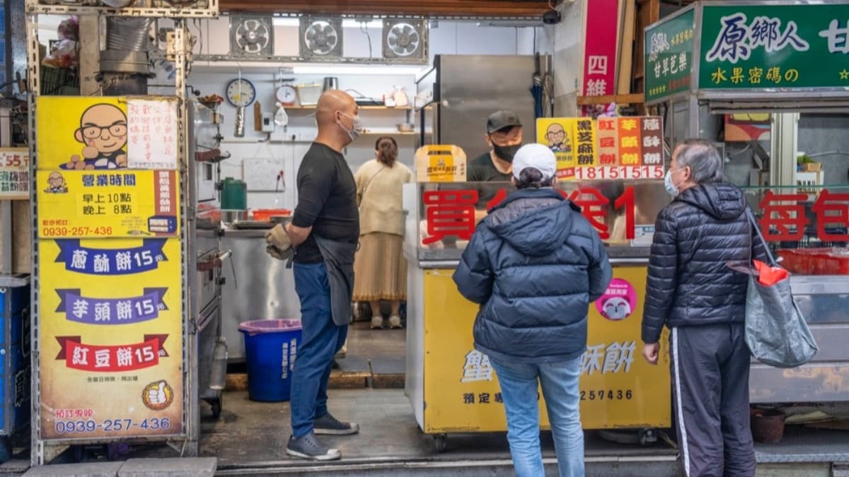 「蟹殼黃蔥酥餅」位在新莊四維市場停車場旁、巷口的水果攤前，相當顯眼。（圖片來源：算命的說我很愛吃）