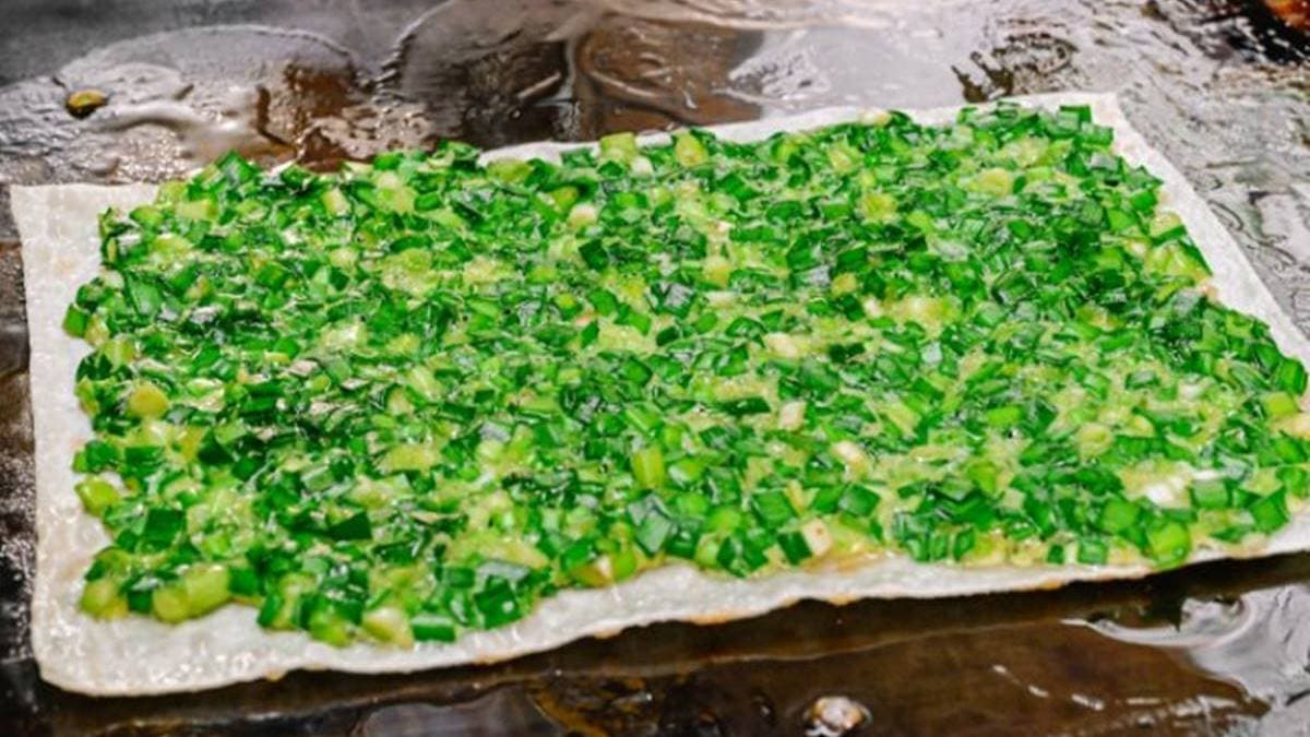 大大的餅皮上鋪滿混合均勻的韭菜與蛋液，給料完全不手軟。（圖片來源：女子的休假計劃