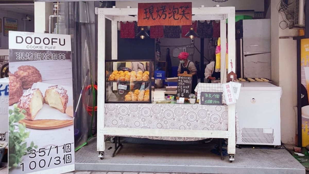店家小小的純白木餐車上，簡單掛著現烤泡芙的招牌。（圖片來源：傻妞吃台南）
