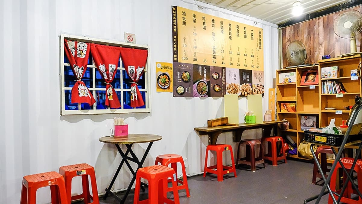 貨櫃屋內有擺放幾張桌子給客人使用，牆面上則有提供品項跟價目表。（圖片來源：霸子。食樂拼圖）