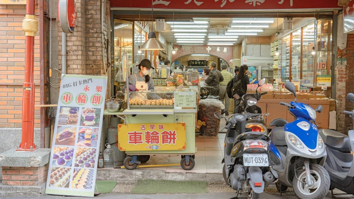 「永樂車輪餅」在中藥行前擺攤，小小的攤子看似突兀，卻有種可愛感。（圖片來源：大妹吃太飽）