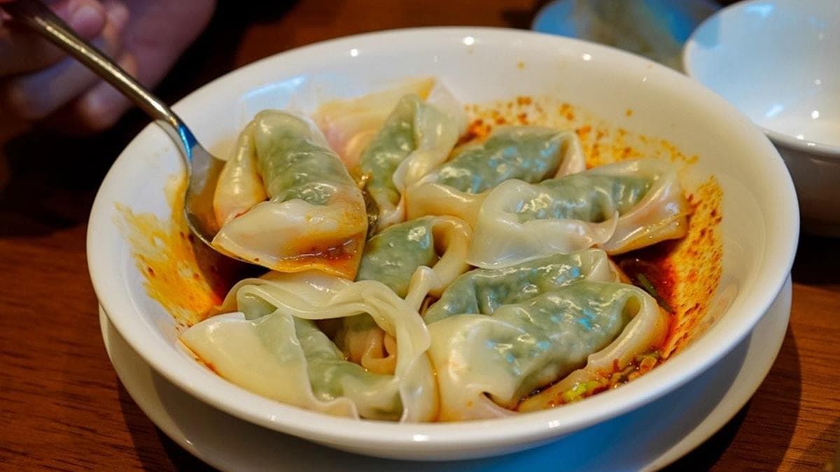 紅油炒手包裹著翠綠的餡料，下頭充滿紅油醬汁。（圖片來源：波妮說食話）