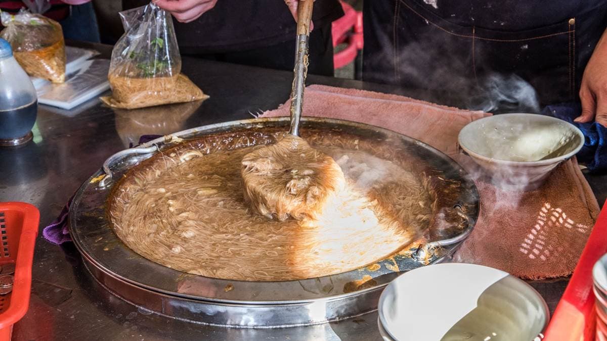 攤位前擺著一大鍋的麵線糊，可以看到店員們俐落地將麵線糊倒在小碗裡。（圖片來源：大手牽小手。玩樂趣）