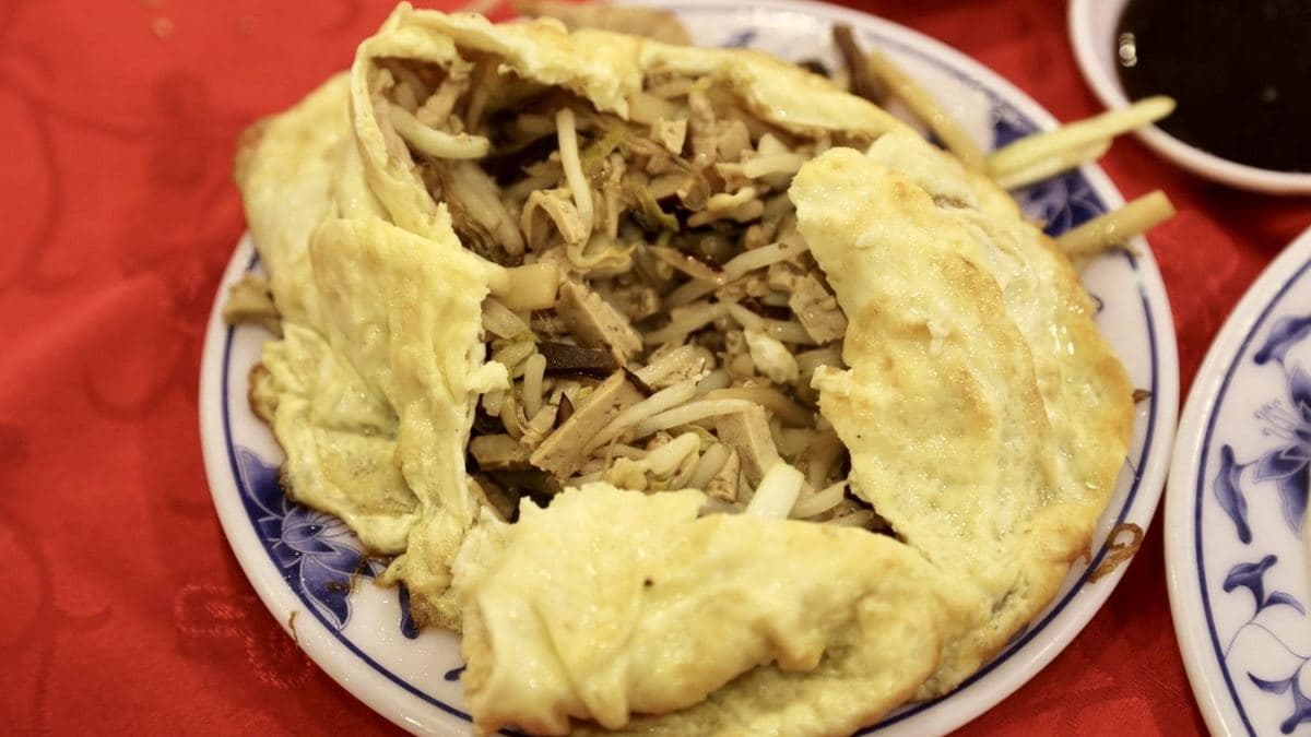 蛋皮底下有豆干絲、肉絲等配料炒在一起，吃的時候可以切開，包在荷葉餅裡面吃。（圖片來源：貓大爺部落格）