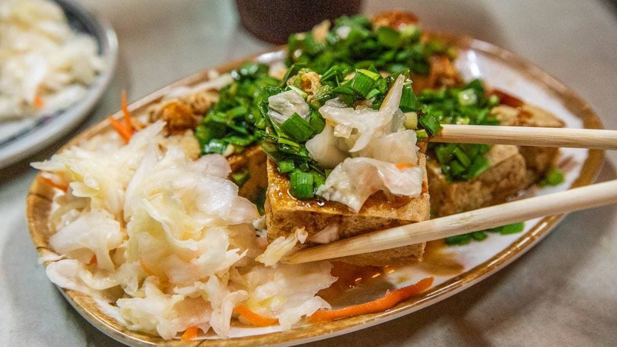 把泡菜、韭菜塞入臭豆腐中央一起吃，２種脆度組合起來一起吃更讚。（圖片來源：大手牽小手。玩樂趣）