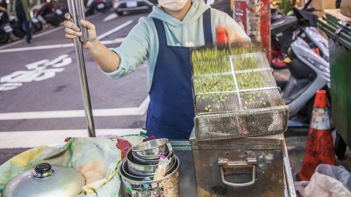 烤碗豆的期間要不斷翻動手上的烤籠，讓豌豆在裡面均勻受熱。（圖片來源：大手牽小手。玩樂趣）