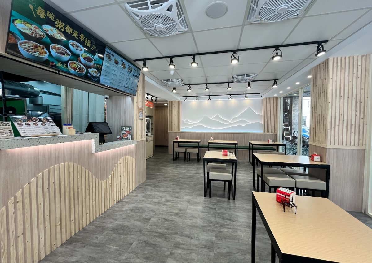 店內裝潢以木質色系為主，搭配深綠色調與立體山景牆面。（圖片來源：粥大福）