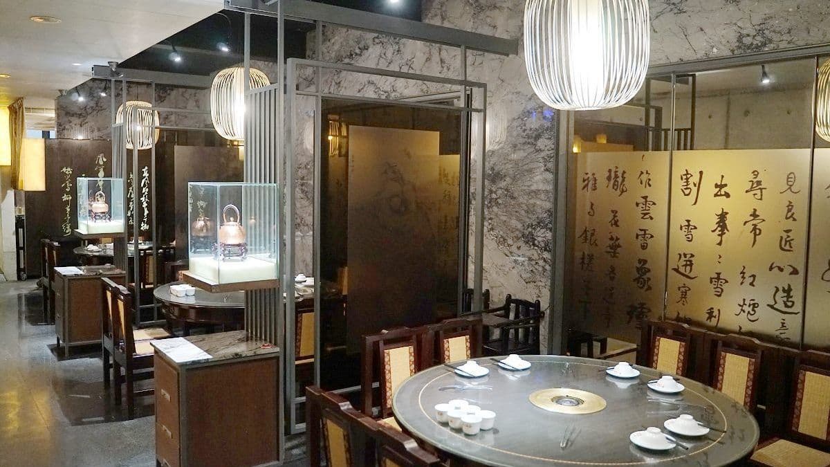店內空間相當古韻典雅，中式圓桌餐桌椅搭配一旁的書法造景。（圖片來源：東蛙池塘）