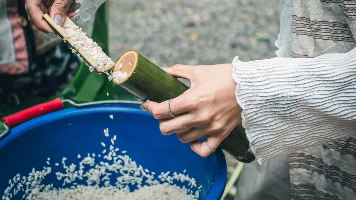 體驗泰雅文化的竹筒DIY，以竹片當湯匙，舀取生糯米及小米倒入竹筒中。（圖片來源：是艾思，不是火拳）